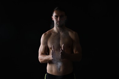 Photo of Man clapping hands with talcum powder before training on black background