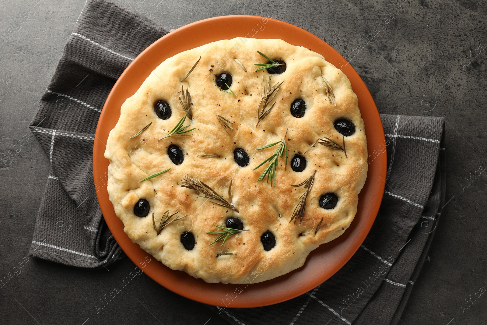 Photo of Delicious focaccia bread with olives and rosemary on grey table, top view