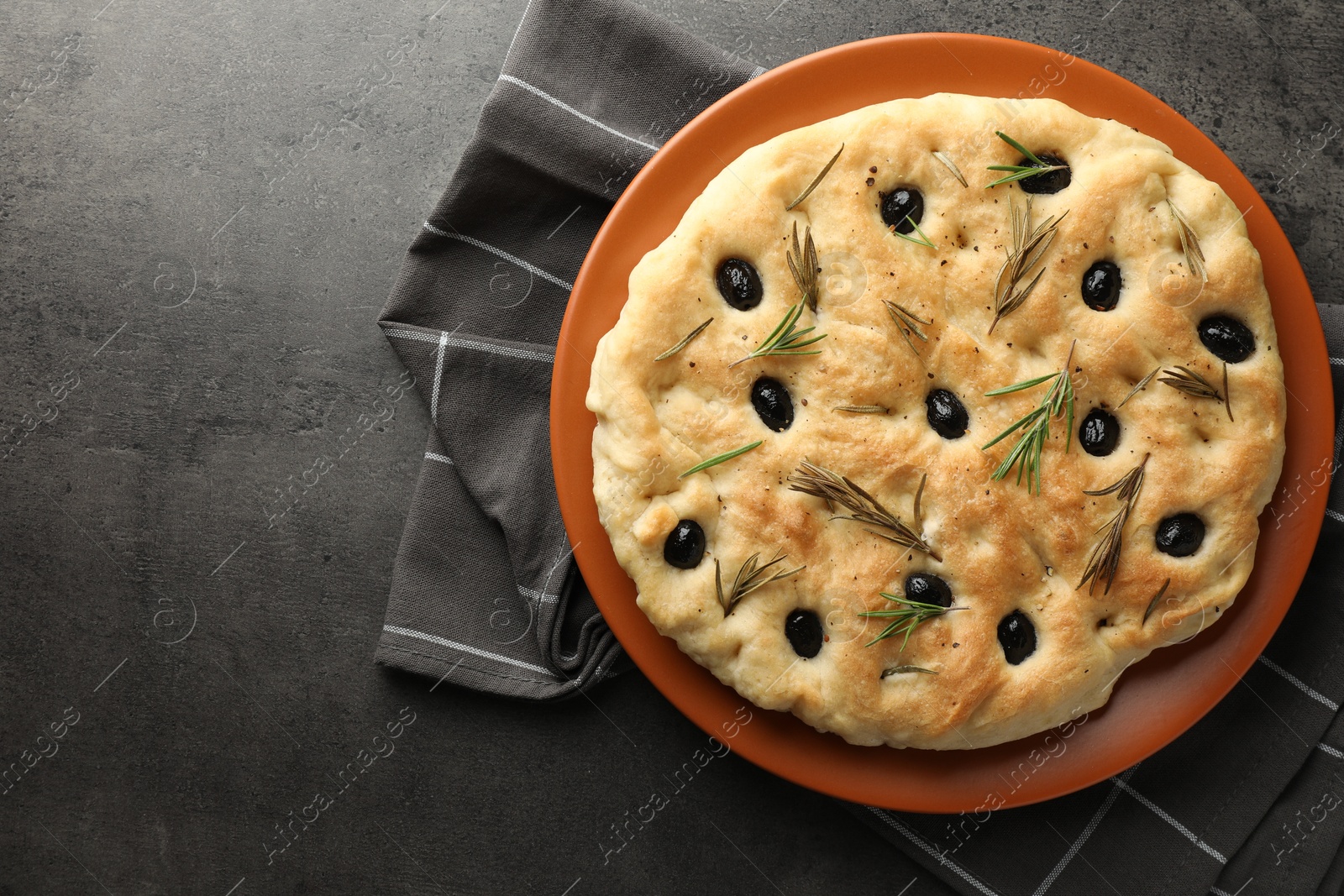 Photo of Delicious focaccia bread with olives and rosemary on grey table, top view. Space for text