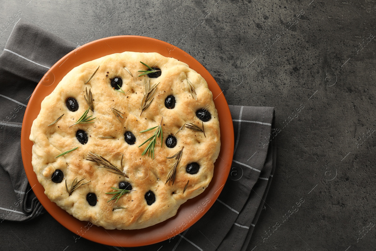 Photo of Delicious focaccia bread with olives and rosemary on grey table, top view. Space for text