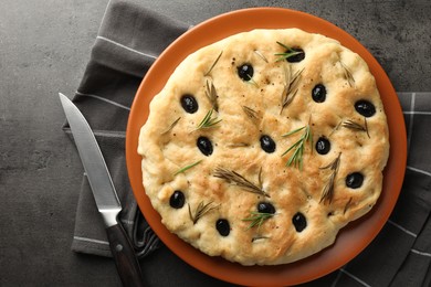 Photo of Delicious focaccia bread with olives, rosemary and knife on grey table, top view