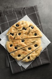 Photo of Slices of delicious focaccia bread with olives and rosemary on grey table, top view