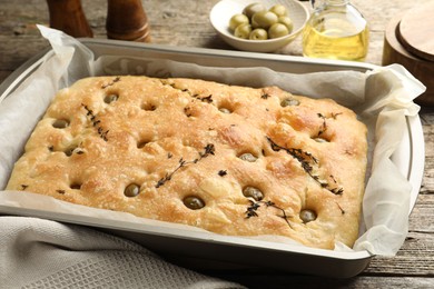 Photo of Delicious focaccia bread with olives and thyme on wooden table, closeup