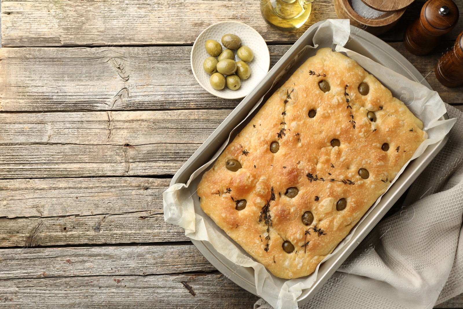 Photo of Delicious focaccia bread with olives, thyme and spices on wooden table, flat lay. Space for text