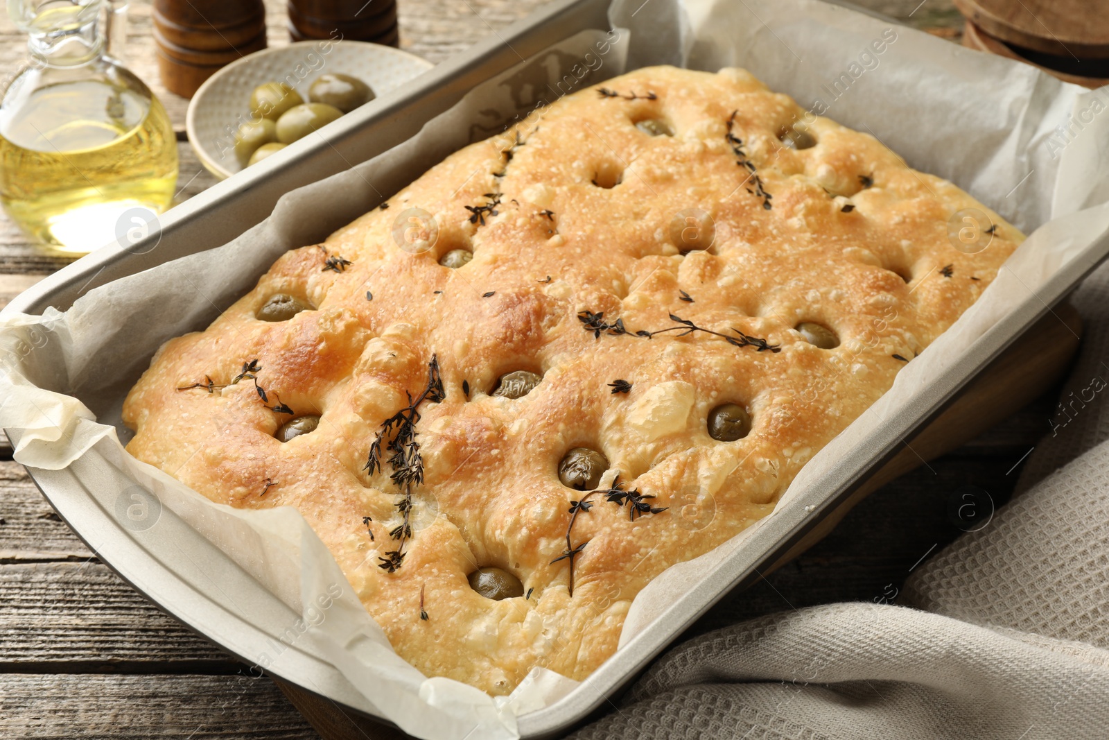 Photo of Delicious focaccia bread with olives and thyme on wooden table, closeup