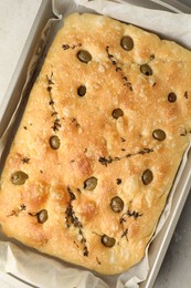 Photo of Delicious focaccia bread with olives and thyme in baking dish on light grey table, top view