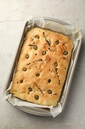 Photo of Delicious focaccia bread with olives and thyme in baking dish on light grey table, top view