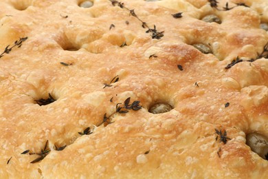 Photo of Delicious focaccia bread with olives and thyme as background, closeup