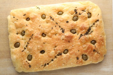 Photo of Delicious focaccia bread with olives and thyme on wooden table, top view