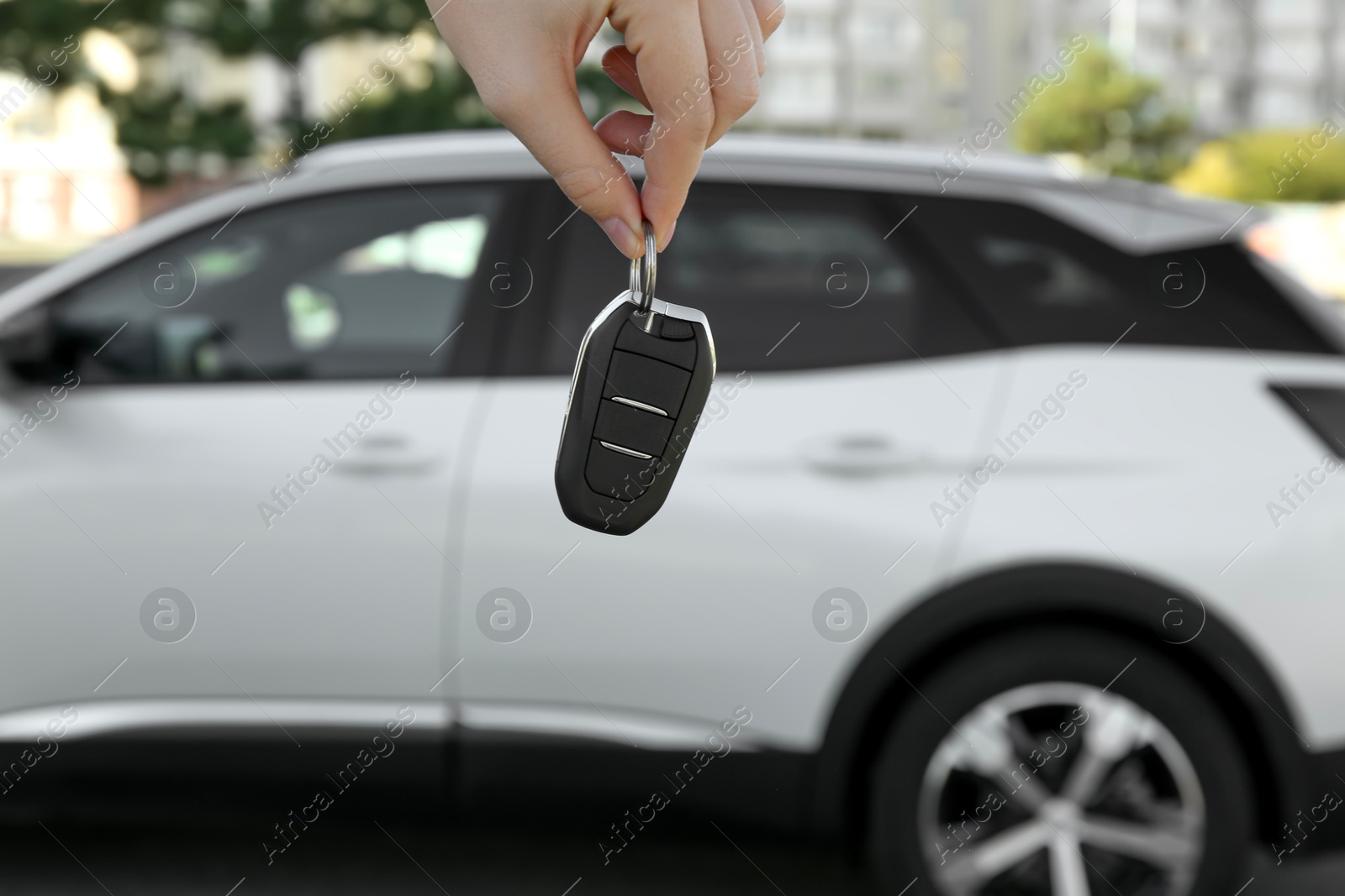 Photo of Woman holding key near car outdoors, closeup