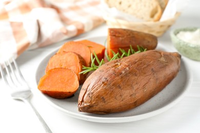 Tasty cooked sweet potatoes and rosemary on white table, closeup