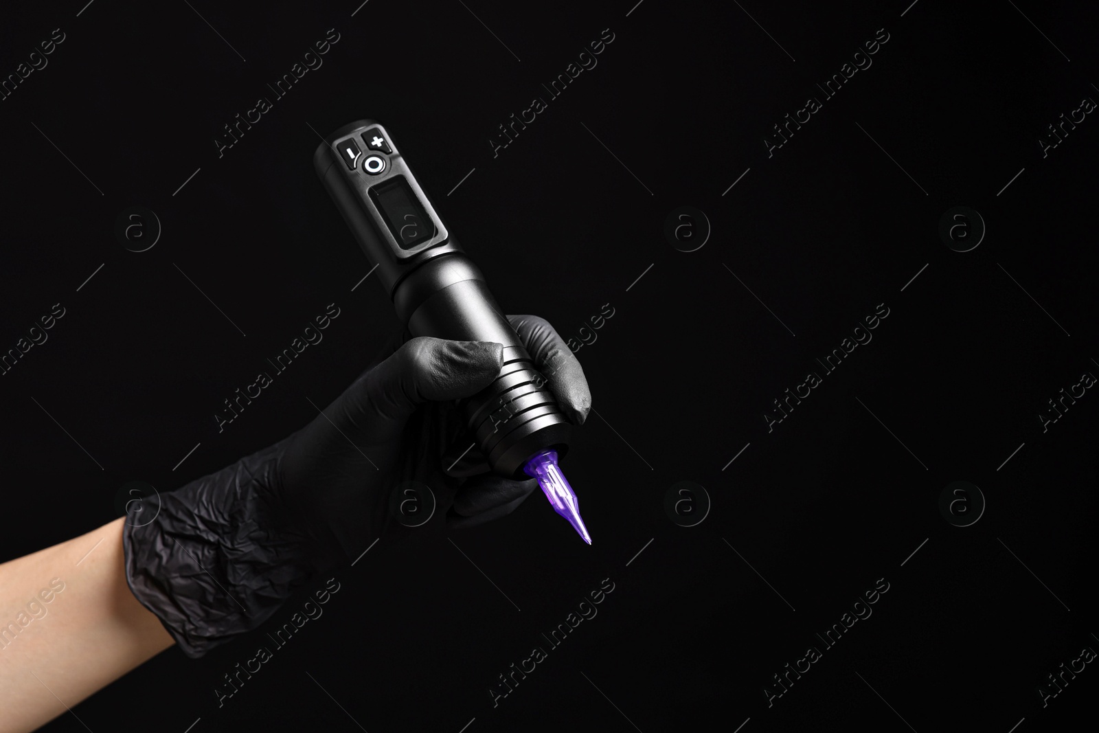 Photo of Professional artist in gloves holding tattoo machine on black background, closeup. Space for text