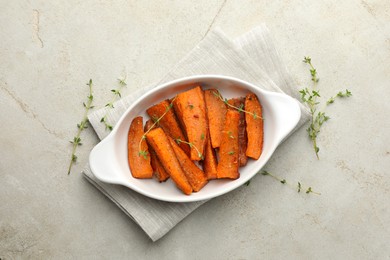 Photo of Pieces of tasty cooked sweet potato in baking dish with microgreens on light textured table, top view