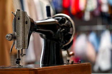 Photo of Vintage sewing machine with thread in workshop, closeup. Space for text