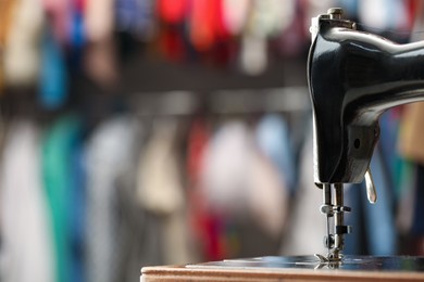 Photo of Vintage sewing machine with thread on blurred background, closeup. Space for text