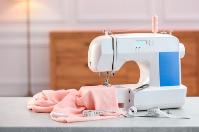 Photo of Sewing machine with fabric and other supplies on white table in workshop