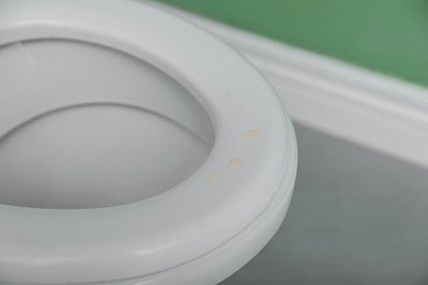 Photo of Urine drops on toilet seat in restroom, closeup