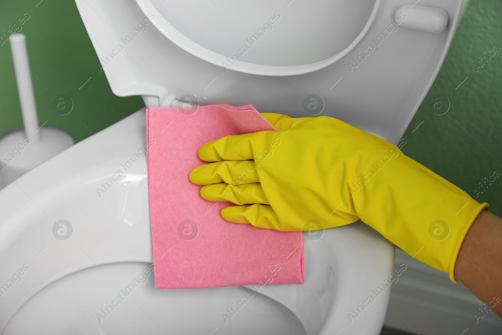 Photo of Woman cleaning toilet seat in restroom, closeup