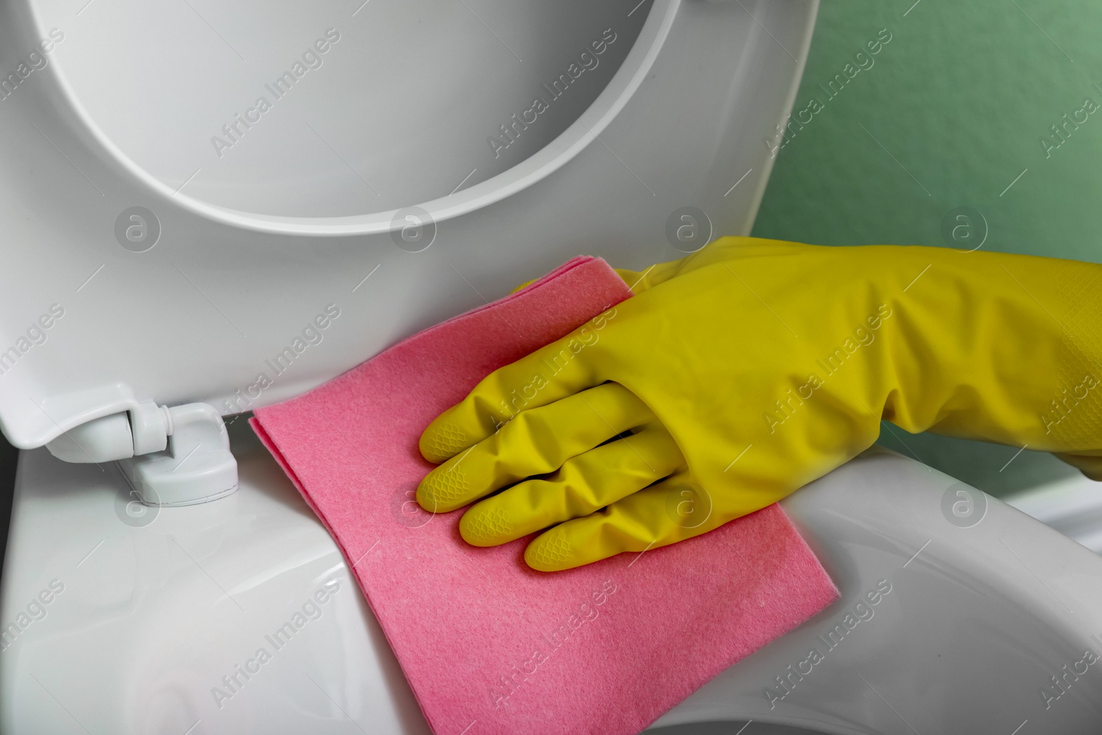 Photo of Woman cleaning toilet seat in restroom, closeup