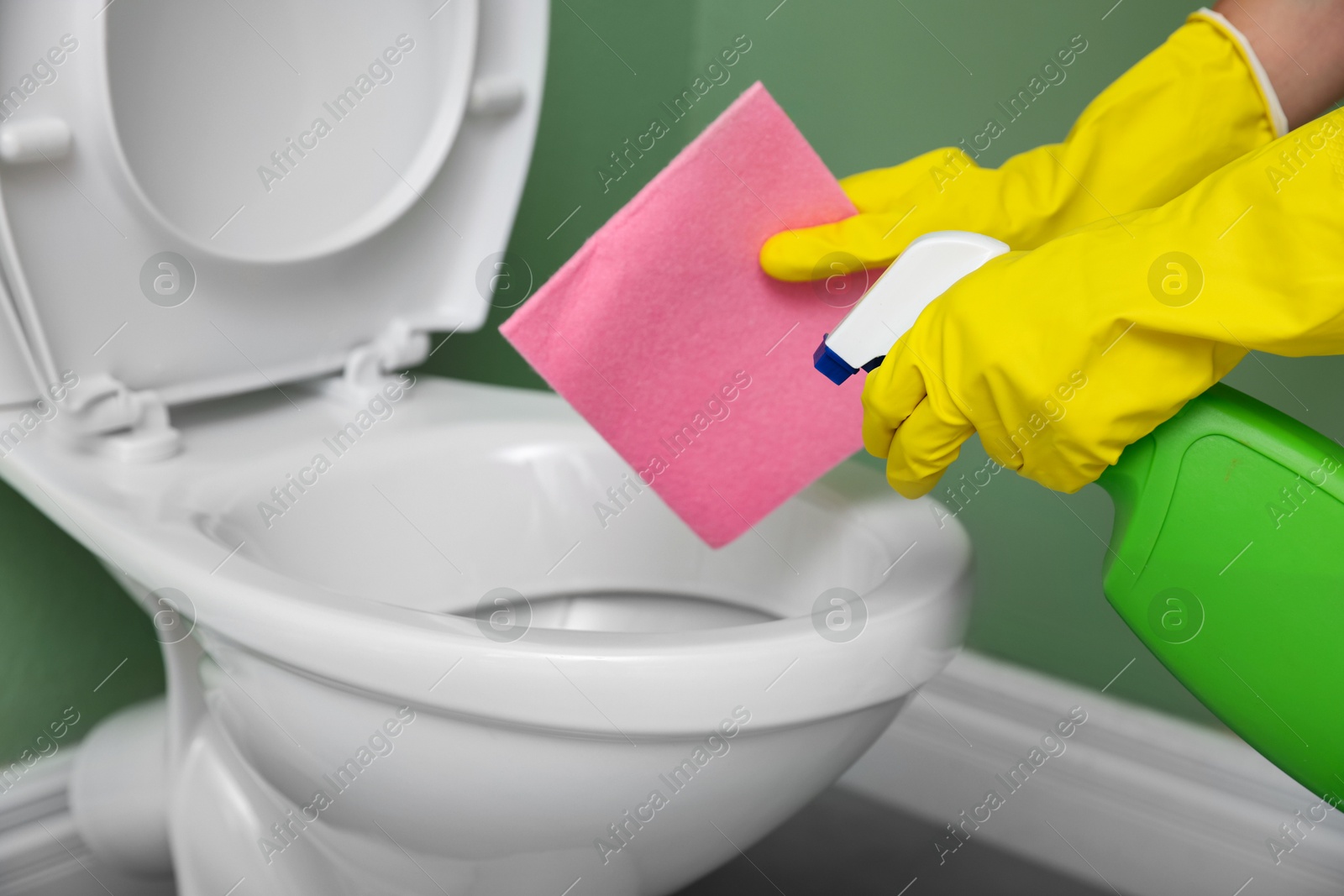 Photo of Woman cleaning toilet bowl in restroom, closeup