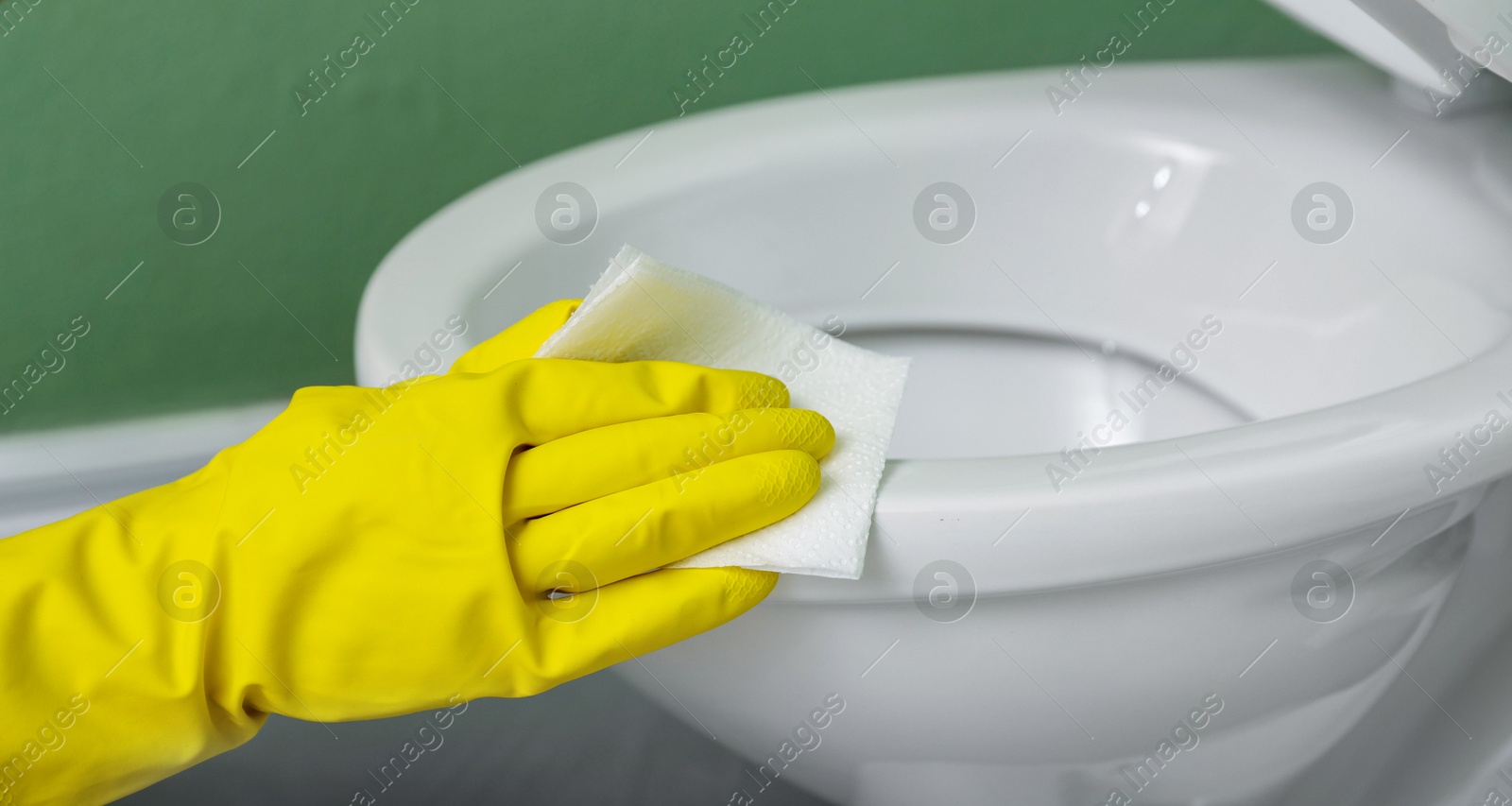 Photo of Woman cleaning toilet bowl in restroom, closeup