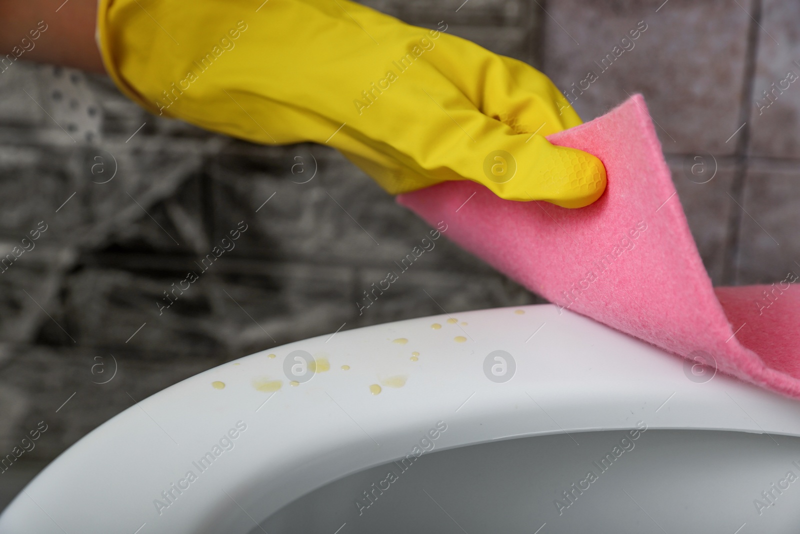 Photo of Woman wiping urine drops from toilet seat in restroom, closeup