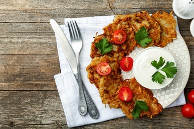 Delicious potato pancakes served on wooden table, flat lay