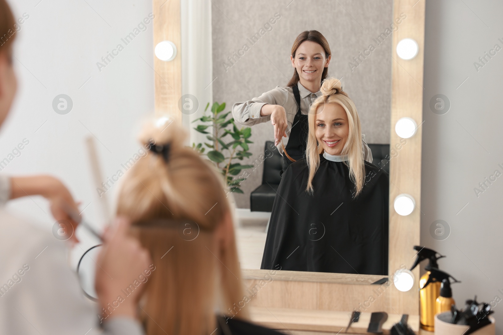 Photo of Hair cutting. Professional hairdresser working with client in salon, selective focus