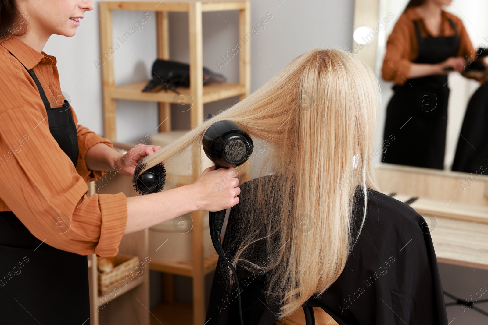 Photo of Hairdresser blow drying client's hair in salon, closeup