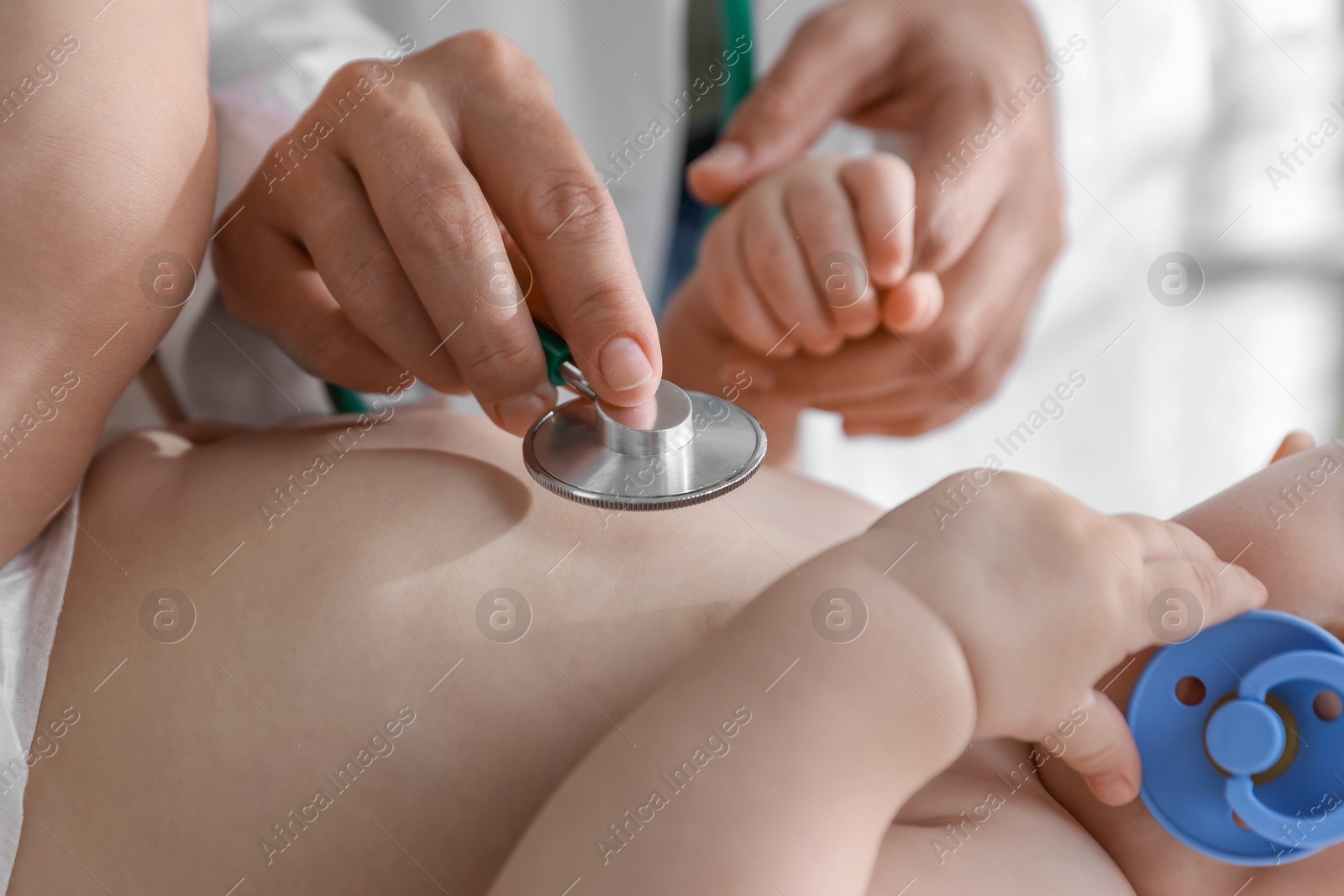 Photo of Pediatrician examining little child with stethoscope in clinic, closeup. Checking baby's health