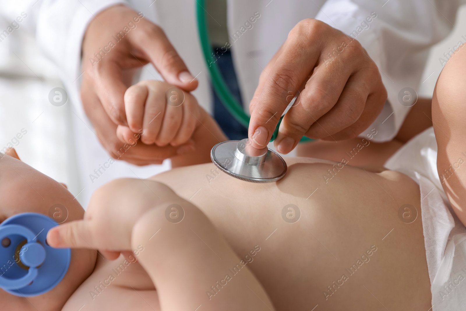 Photo of Pediatrician examining little child with stethoscope in clinic, closeup. Checking baby's health