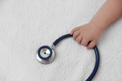 Photo of Little child with stethoscope on towel, closeup. Checking baby's health