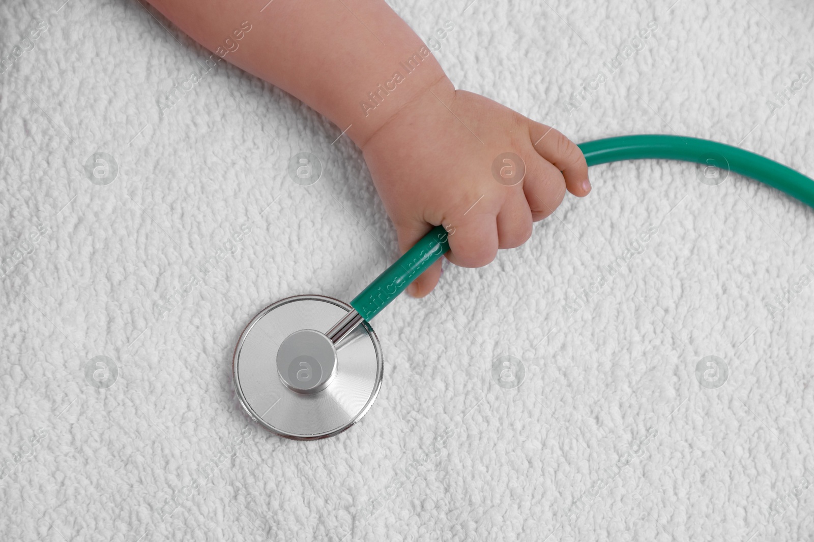 Photo of Little child with stethoscope on towel, top view. Checking baby's health