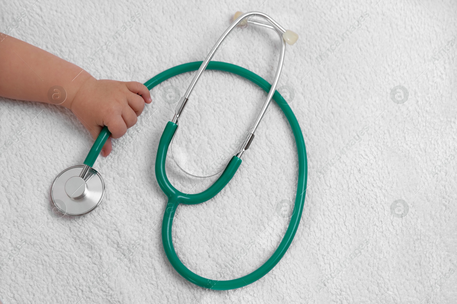 Photo of Little child with stethoscope on towel, top view. Checking baby's health