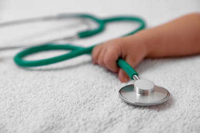 Photo of Little child with stethoscope on towel, closeup. Checking baby's health