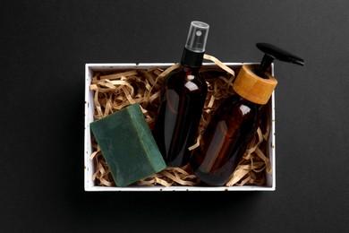 Photo of Cosmetic products in box as Christmas gift on black background, top view