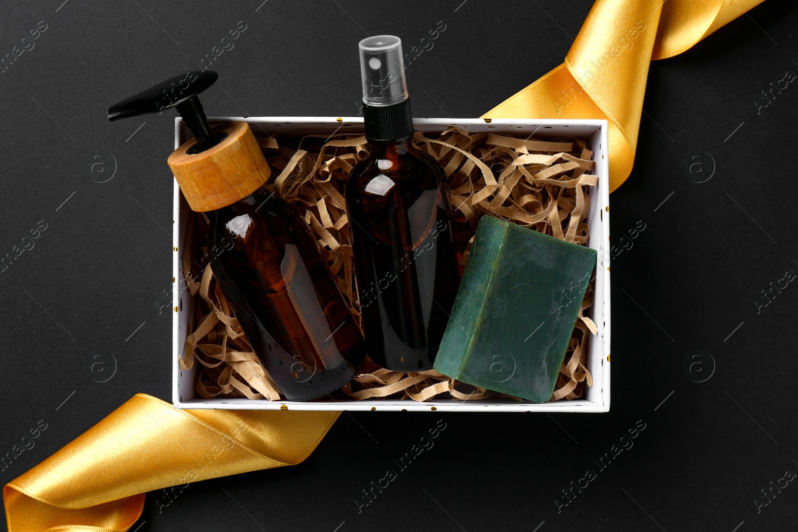 Photo of Cosmetic products in box as Christmas gift on black background, top view