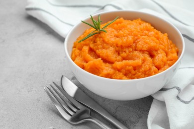 Photo of Tasty mashed sweet potato with rosemary in bowl served on grey textured table, closeup