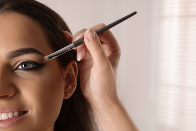 Photo of Artist doing makeup on woman's face indoors, closeup