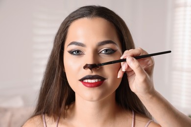 Photo of Artist doing cat makeup on woman's face indoors