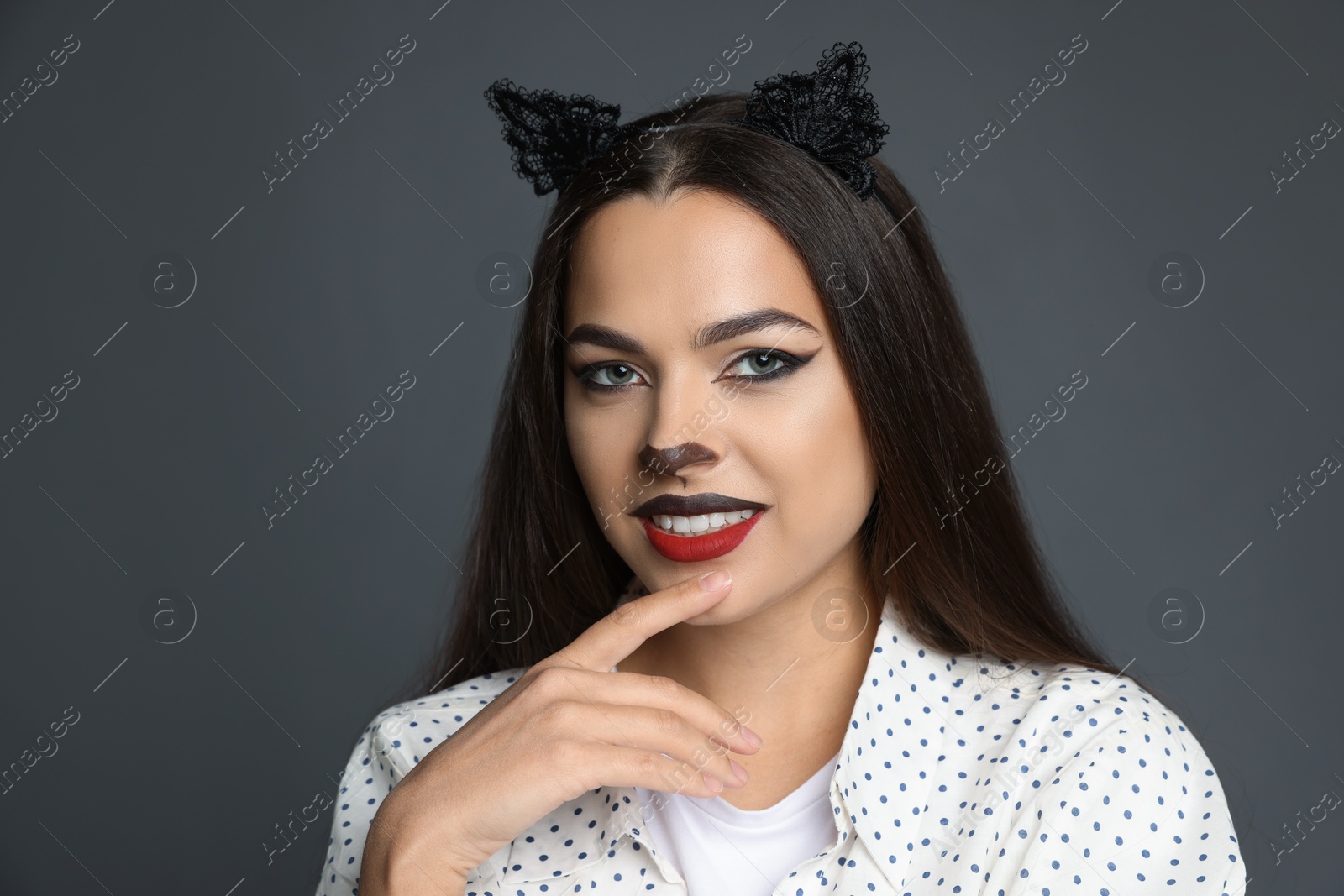 Photo of Attractive woman with cat makeup and ears on grey background