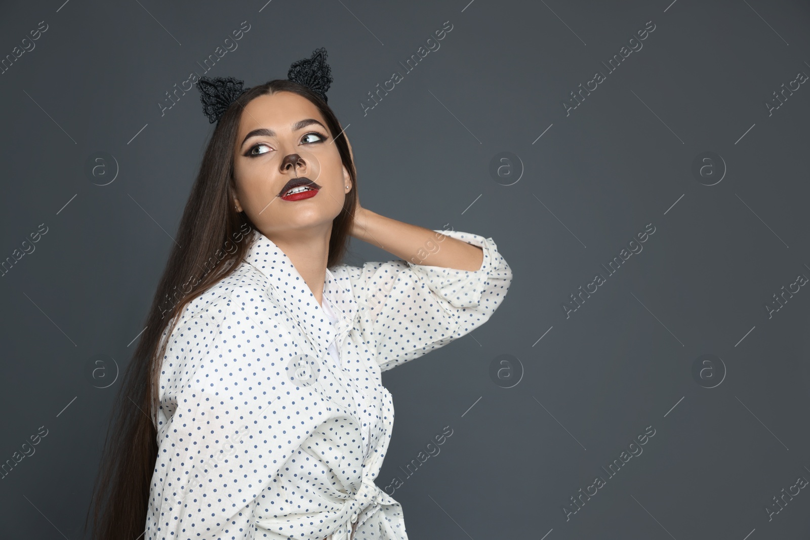 Photo of Attractive woman with cat makeup and ears on grey background. Space for text