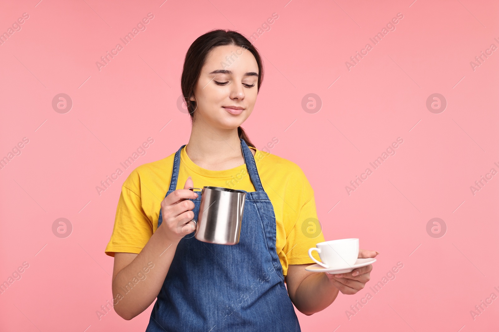 Photo of Girl in apron with pitcher and cup of coffee on pink background. Work for teenagers