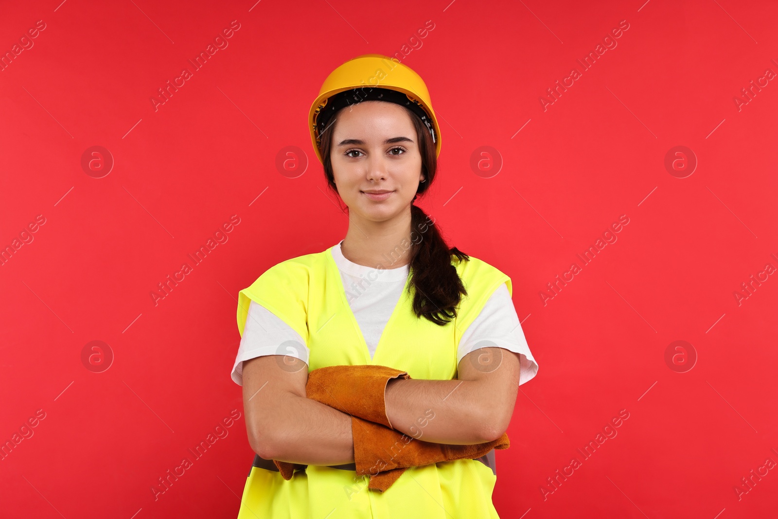 Photo of Girl with safety equipment on red background. Work for teenagers