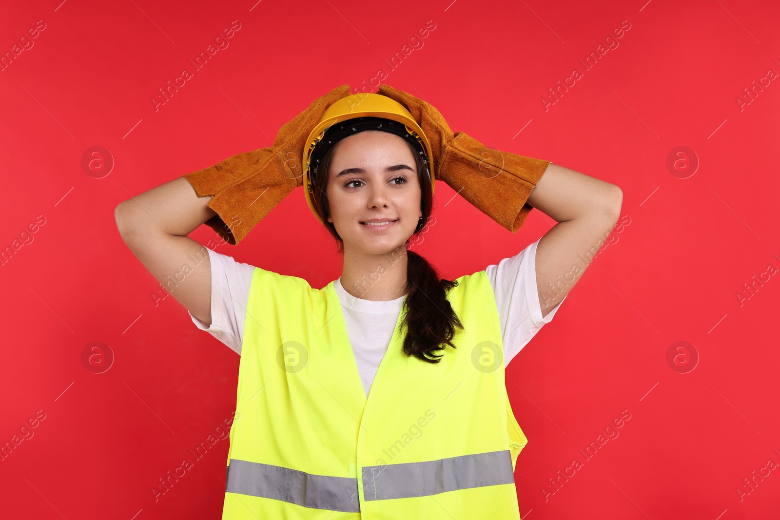 Photo of Girl with safety equipment on red background. Work for teenagers