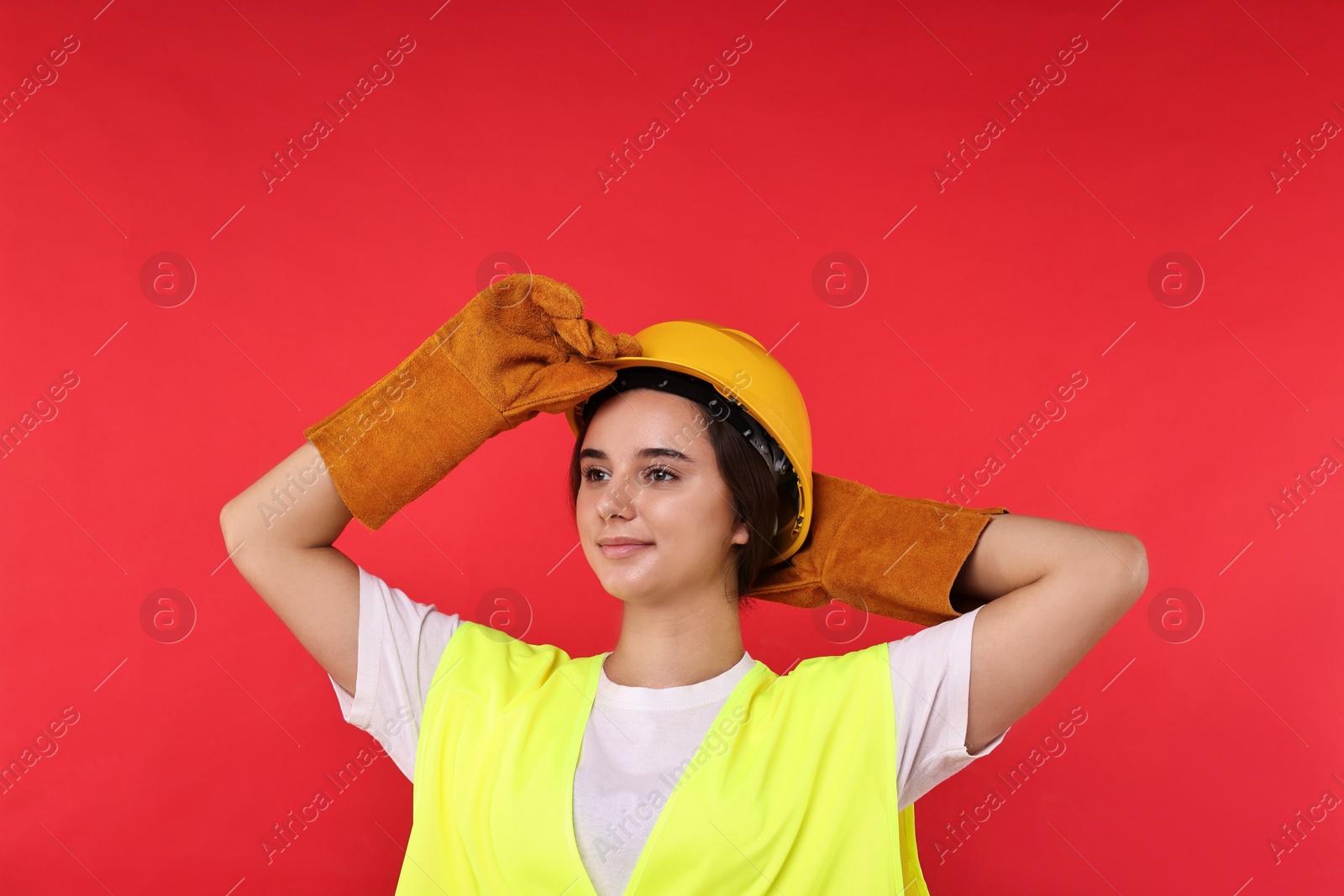 Photo of Girl with safety equipment on red background. Work for teenagers