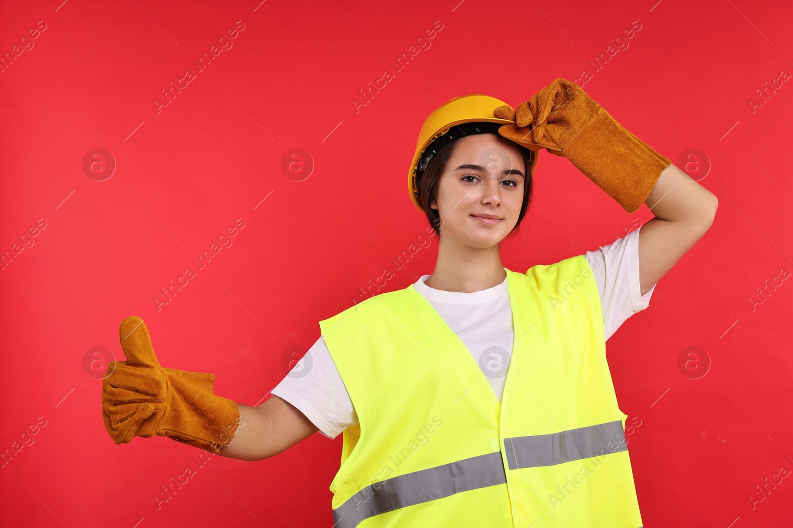 Photo of Girl with safety equipment showing thumbs up on red background. Work for teenagers