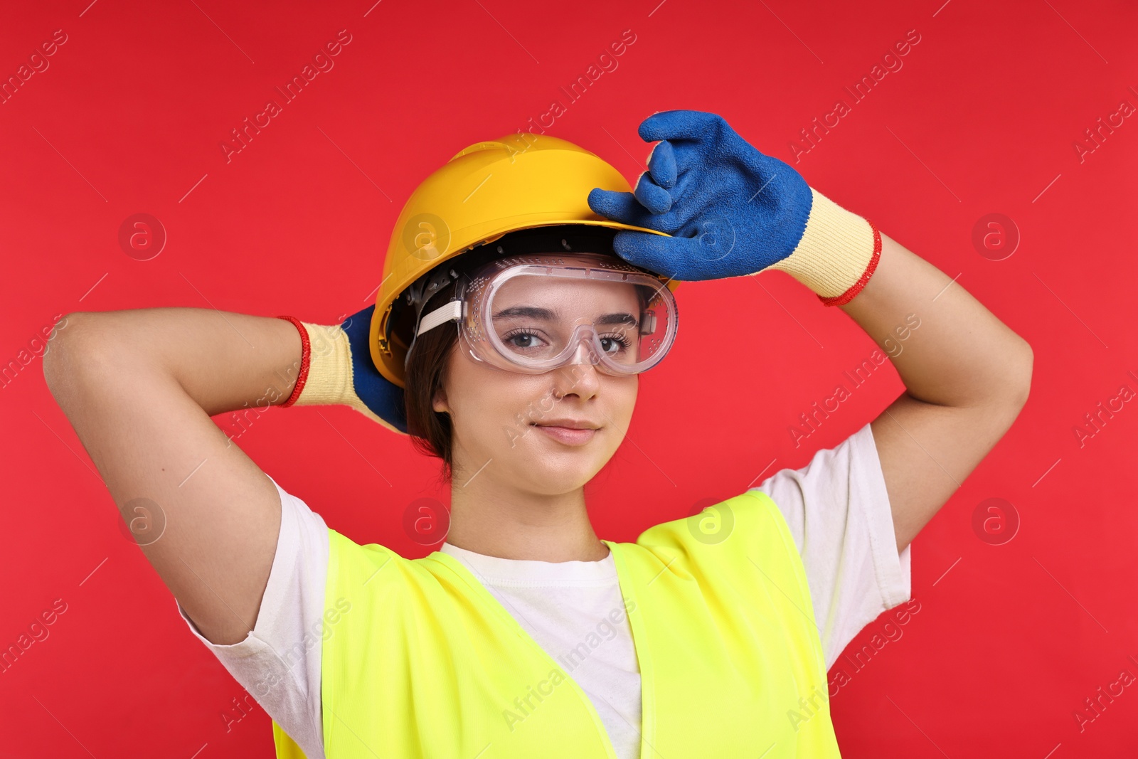 Photo of Girl with safety equipment on red background. Work for teenagers