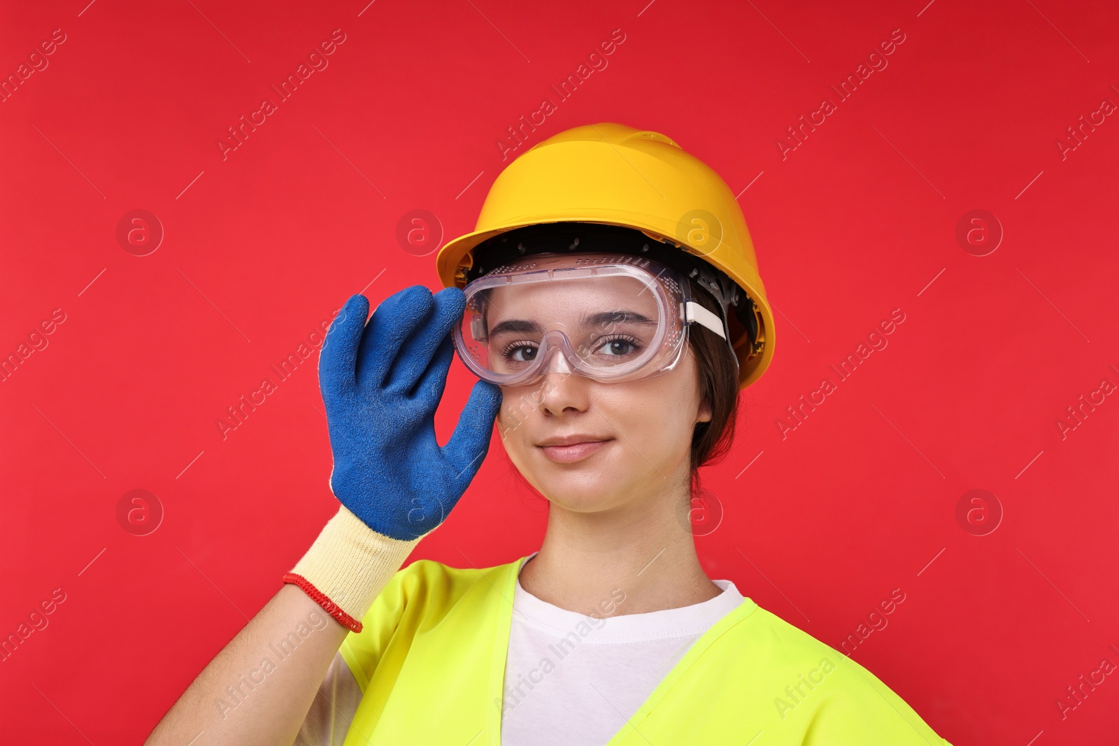 Photo of Girl with safety equipment on red background. Work for teenagers