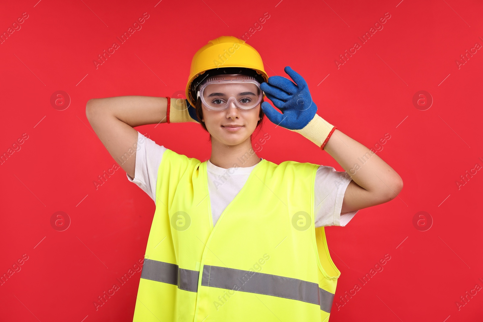 Photo of Girl with safety equipment on red background. Work for teenagers